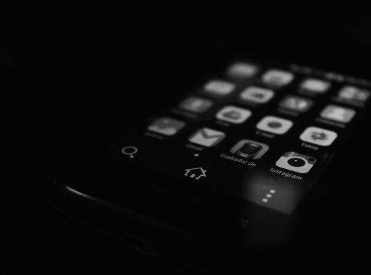 A black and white image of a mobile phone screen showing apps.