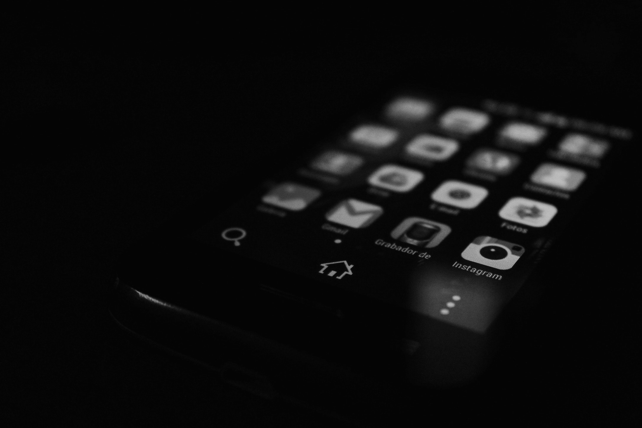 A black and white image of a mobile phone screen showing apps.