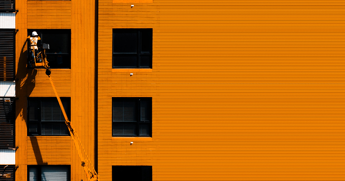 A construction worker on an orange building