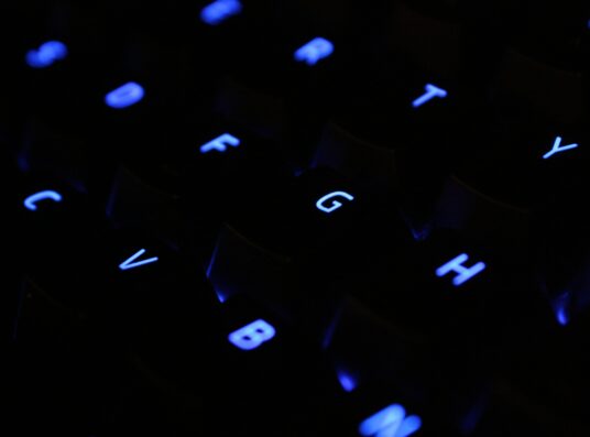 A close-up of a computer keyboard with light-up blue keys