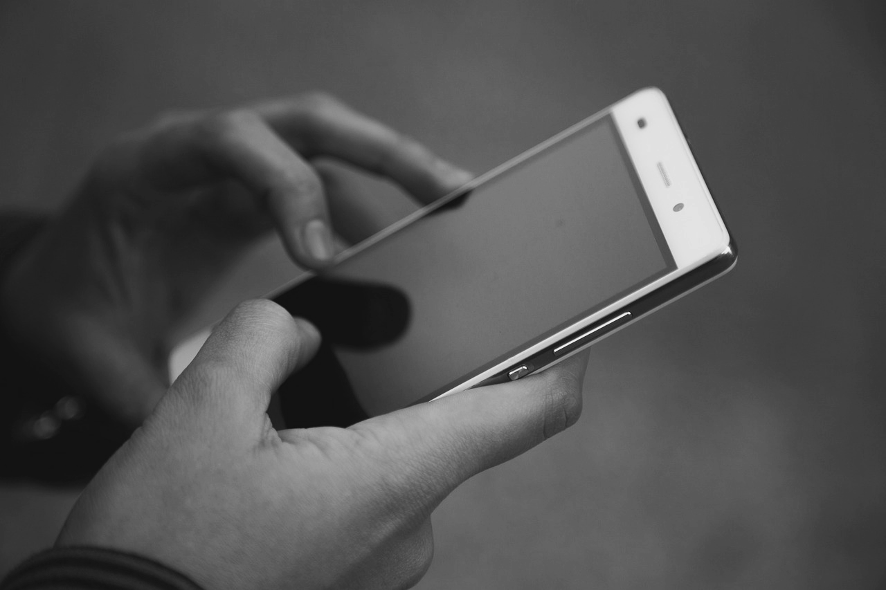 A black and white picture of hands using a mobile phone.